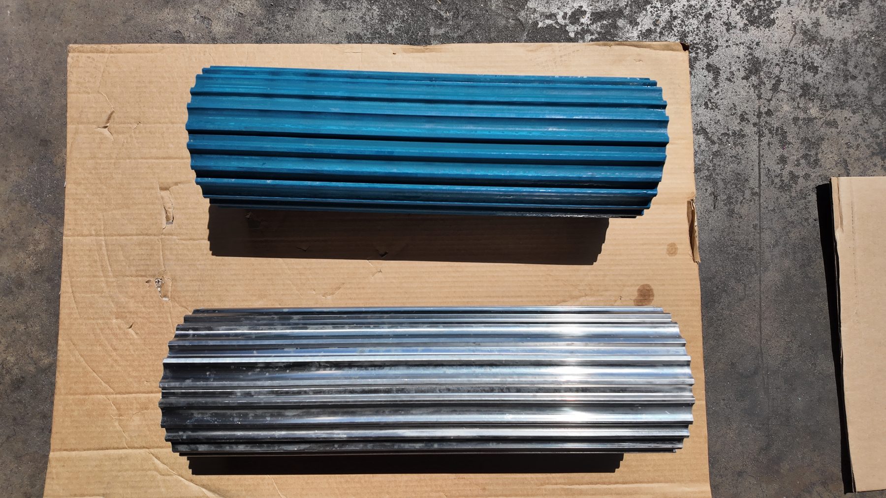 Two fluted drum motor lagging profiles side by side, blue coated and bare aluminum
