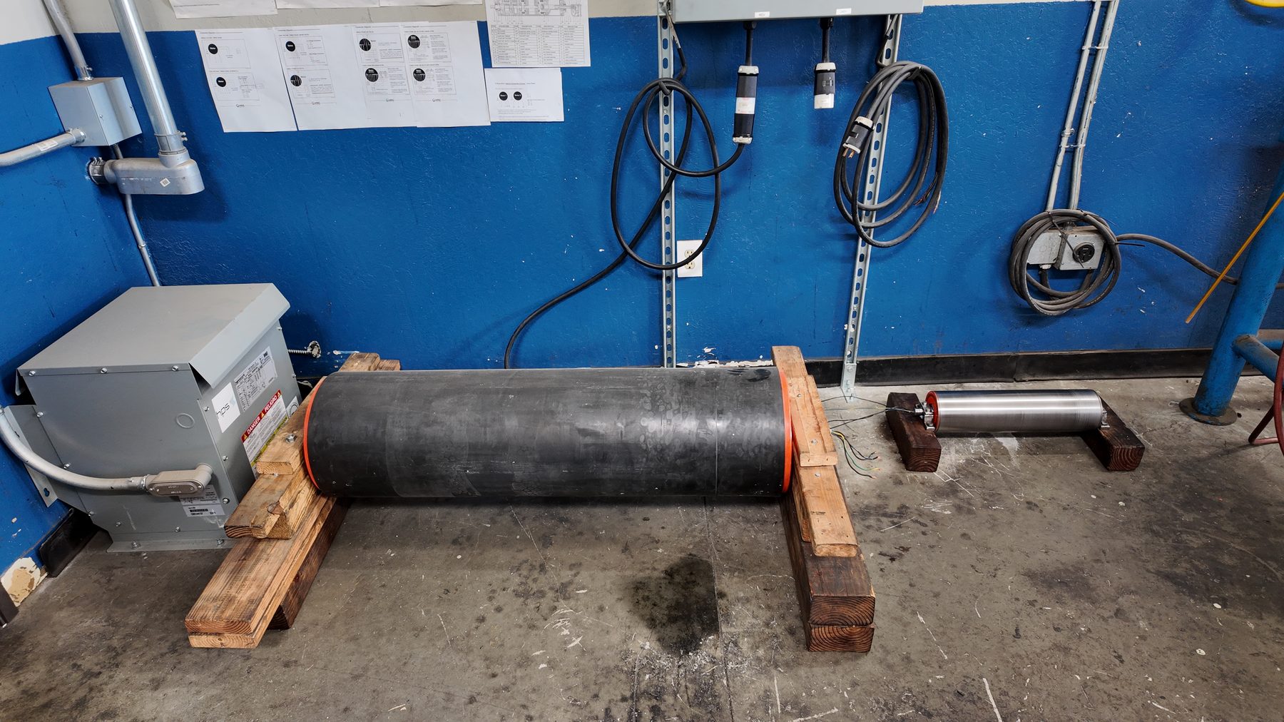 A large lagged drum motor beside a small stainless unit, showing the range of sizes repaired