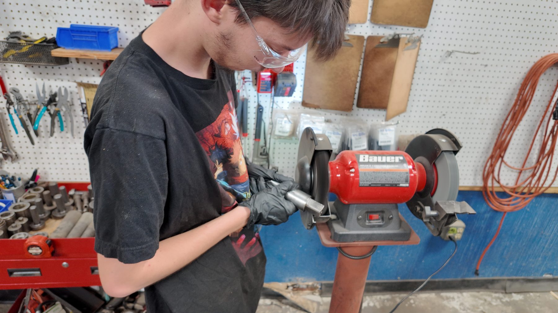Technician dressing a drum motor shaft on the bench grinder
